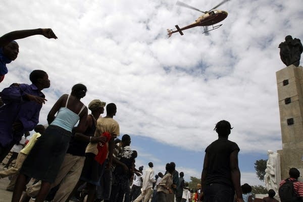 Earthquake survivors wave to a helicopter