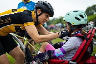 A woman helps fix a child's helmet