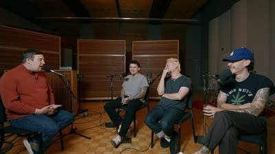 Four men have a conversation in a recording studio