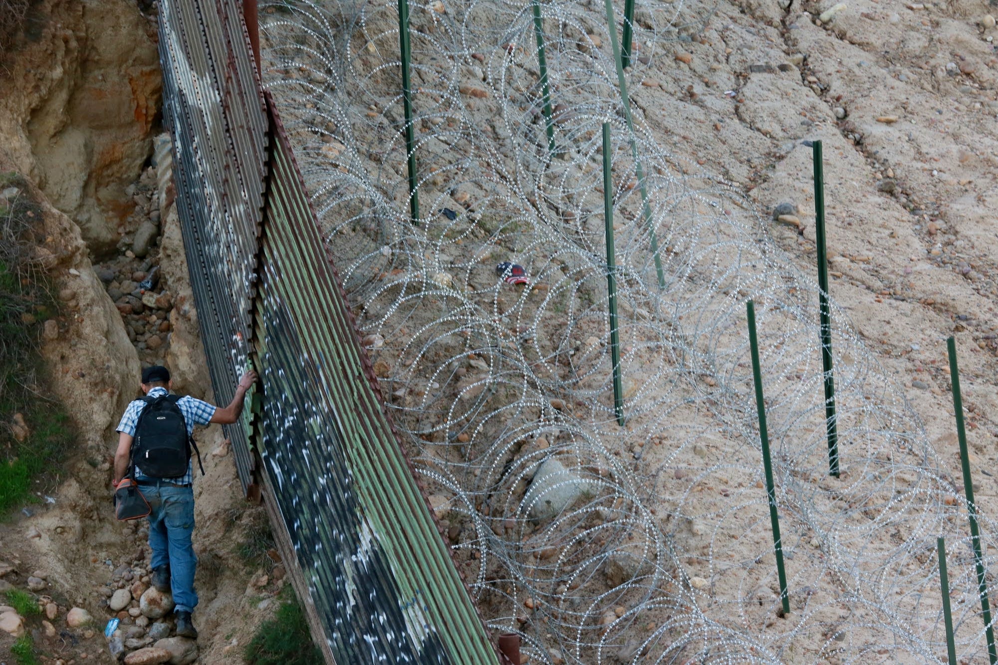 A man walks along the U.S.-Mexico border wall.