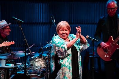 Three musicians performing together onstage in a concert hall