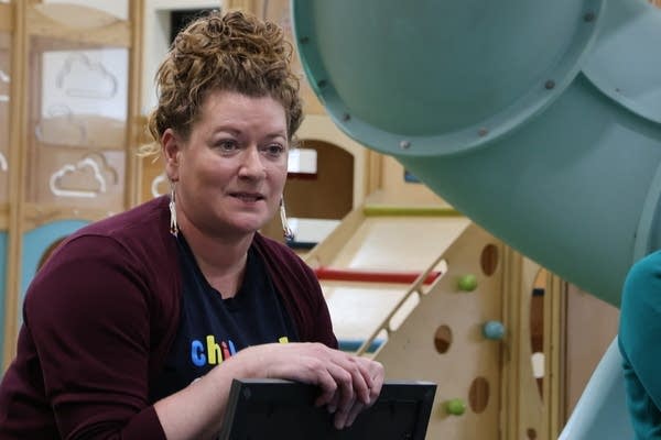 A woman sits next to a children's playground.