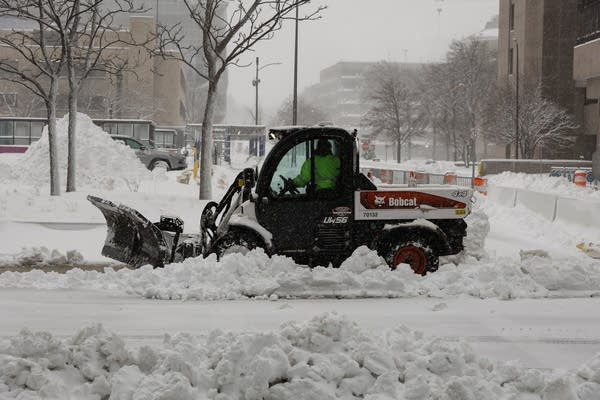A snowplow drives through a city street.