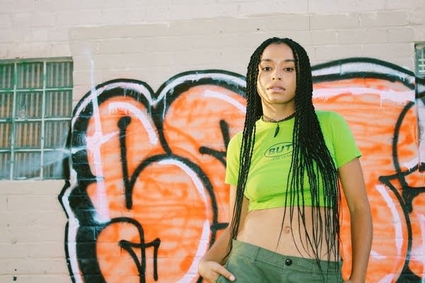 Portrait of a person standing in front of a wall with graffiti art