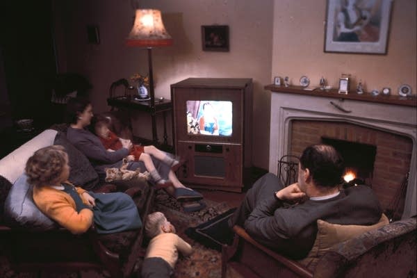 A family of five relax in front of their color television.