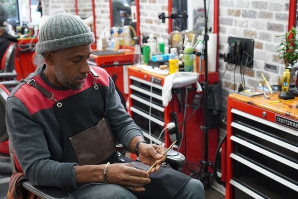 A middle aged Black man seated inside a barber shop a tool
