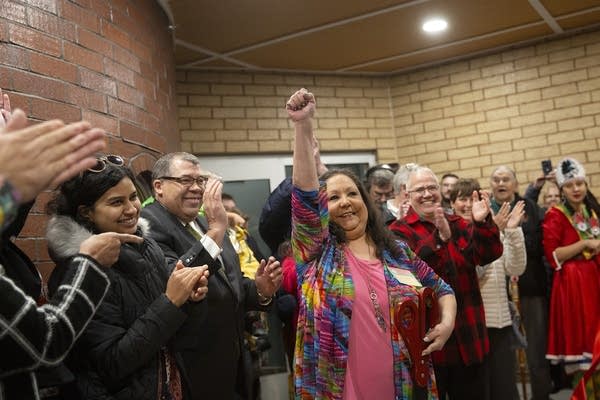 A woman raises her fist as people around her clap.