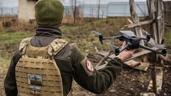 A Ukrainian serviceman holds a drone in their right hand.