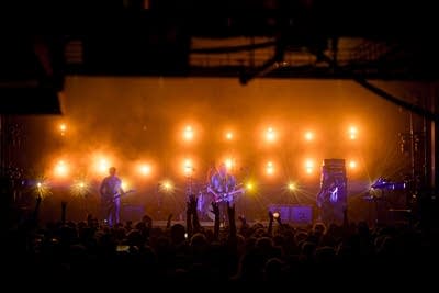 Band performing on stage with bright lights behind them
