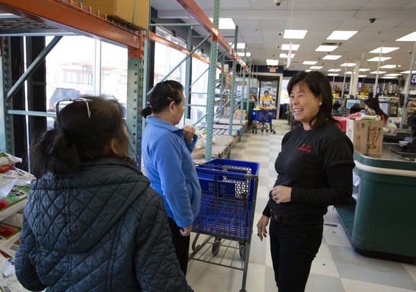 A woman talking to two people near empty shelves at a store. 