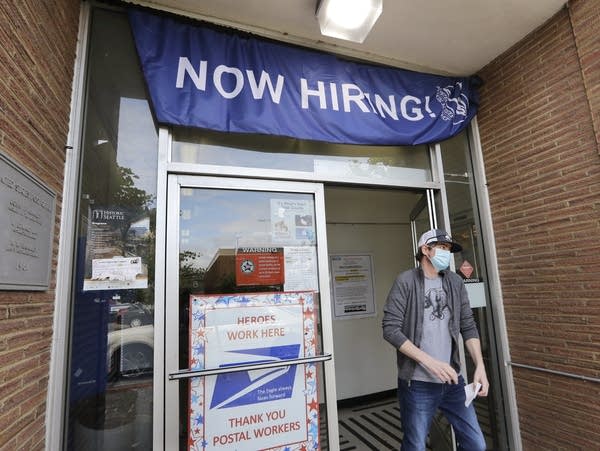 A man with a face mask walks out of a post office.