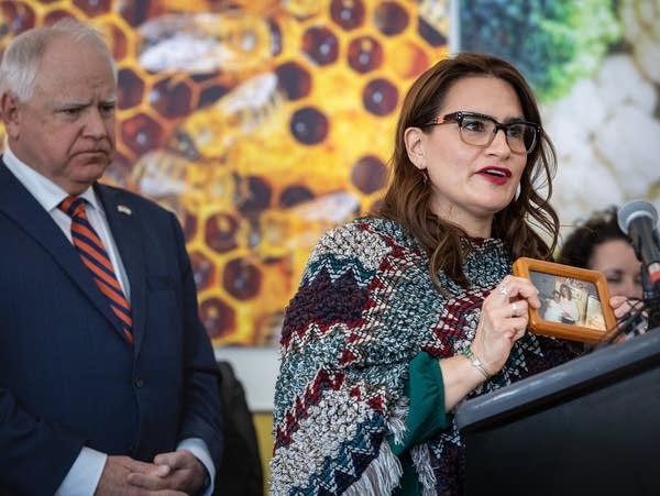 A woman at a podium holds up a picture 