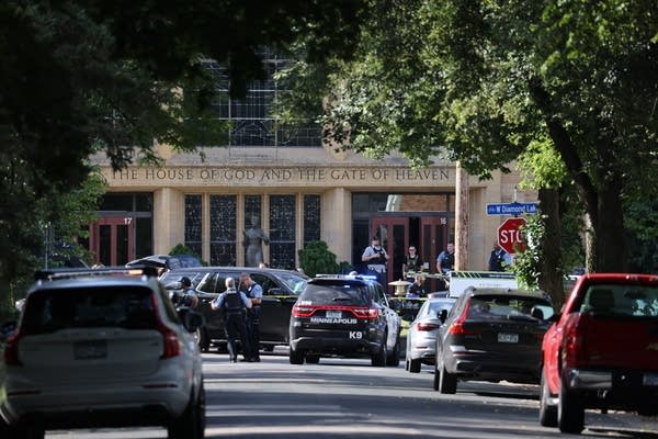 A stree with a number of police vehicles and a building at the end.