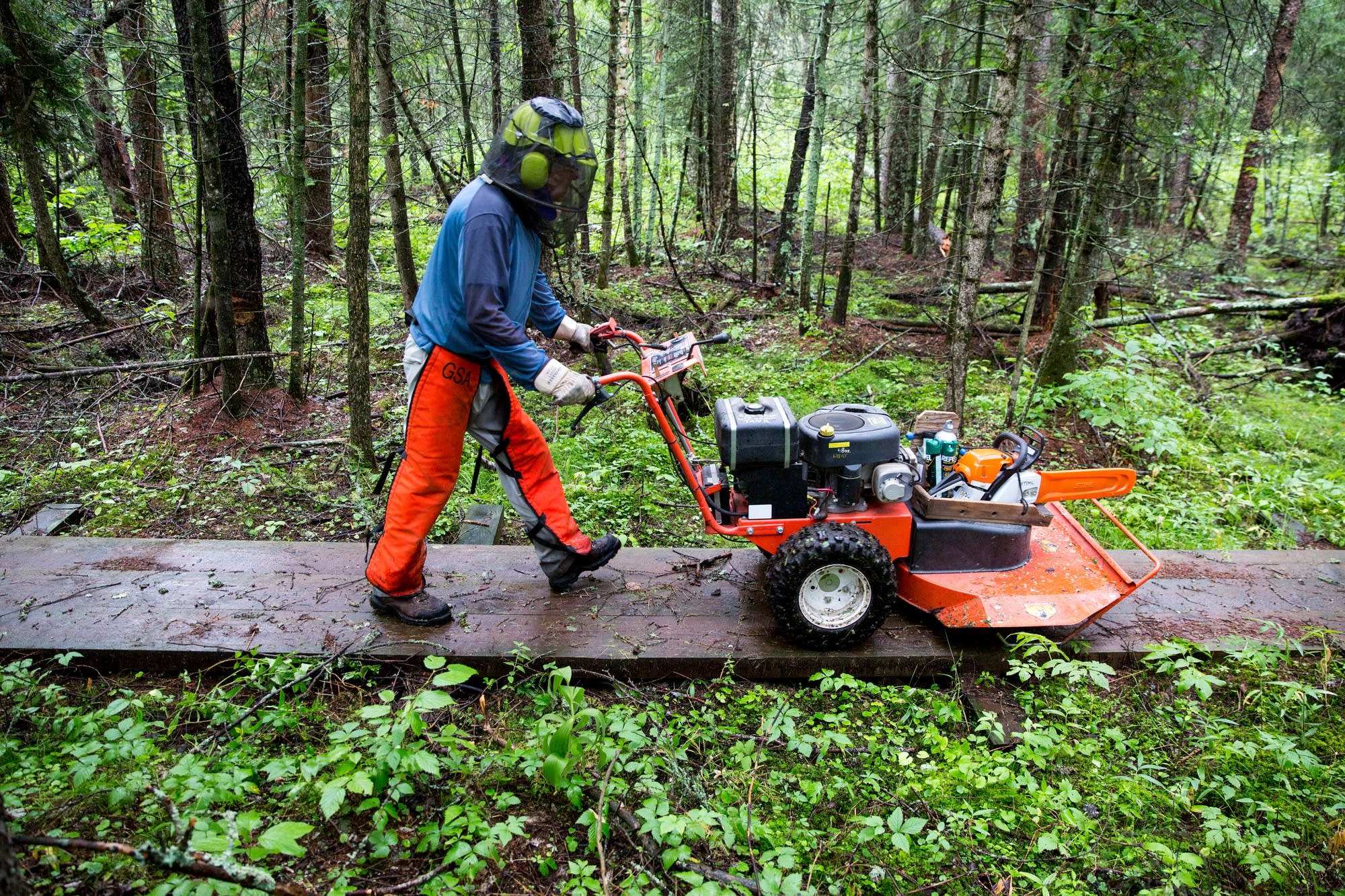 Jim Rakness pushes a mower down a puncheon