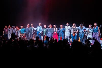 A large group of musicians take a bow onstage