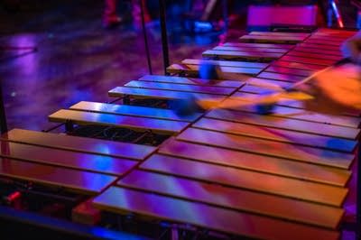 Hands striking a vibraphone with mallets 