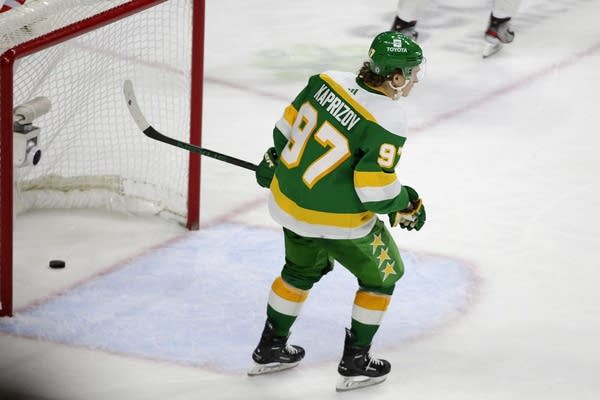 A hockey player skates past an empty net.