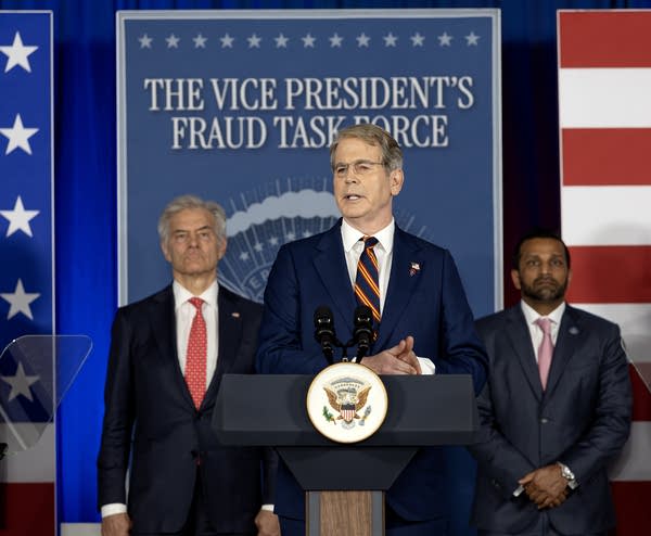 men in suits stand near a podium
