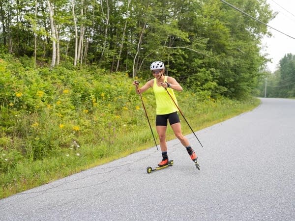 Jessie Diggins roller skiing down a country road in summer.
