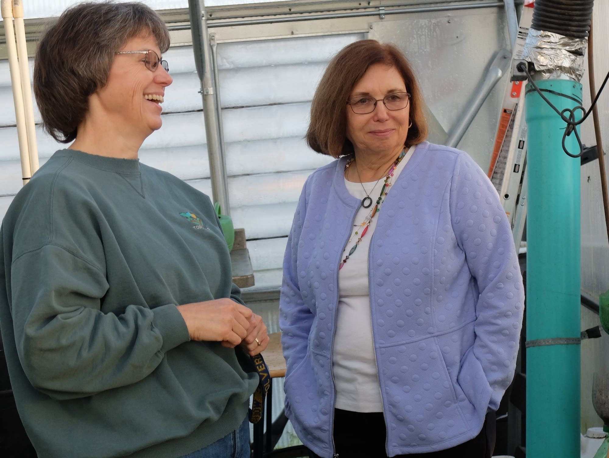 Caroline Venis and Sandie Rentz share a laugh in the greenhouse.