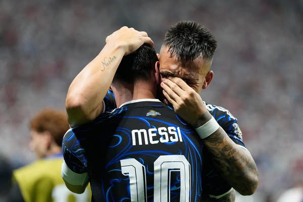Two soccer players hug in tears.
