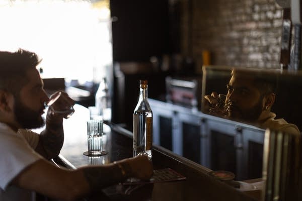 A man's reflection is seen in a bar