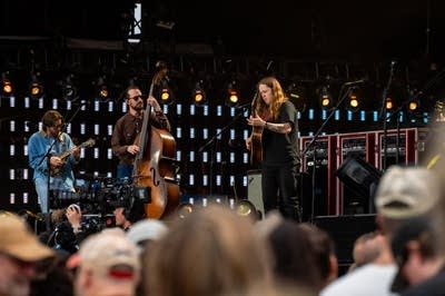 Three musicians performing on a large outdoor stage