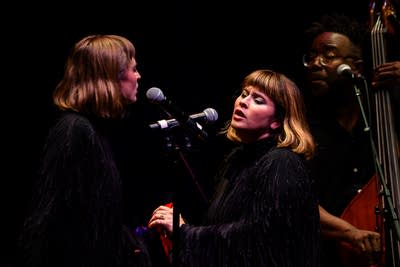 Three musicians performing together onstage in a concert hall