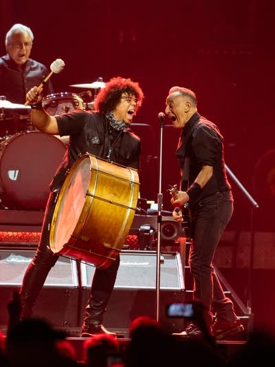 Three musicians performing onstage during an arena concert