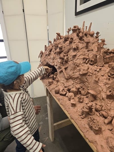 A child touches a large clay sculpture.