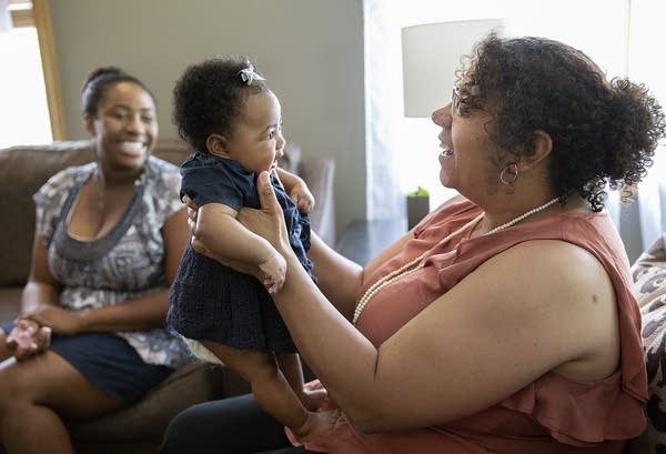 A woman holds a baby on her lap. 