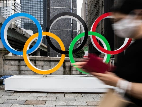 A person walks by a monument of the Olympic Rings.