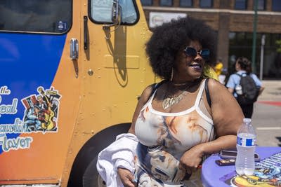 A woman stands next to a food truck.