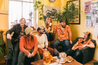 Six people sit together casually in a sunny room