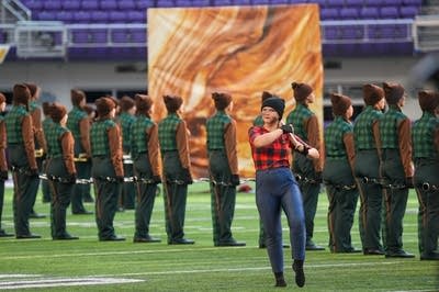 A marching band performs on the field of a football stadium.