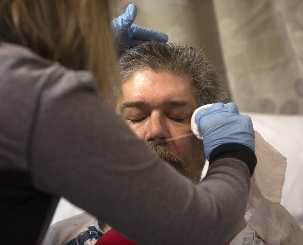 ICU patient Daniel Hage has his face washed.