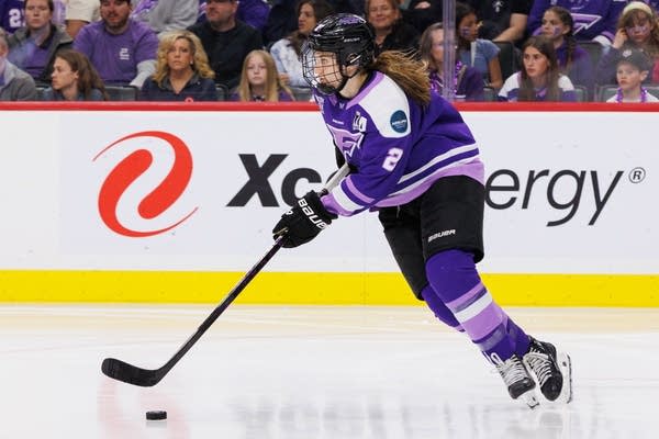 A hockey player skates with the puck.
