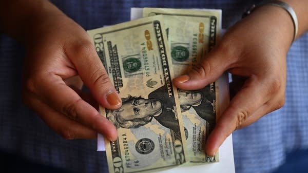 A woman counts cash outside a U.S. remittance collection agency in El Salvador.
