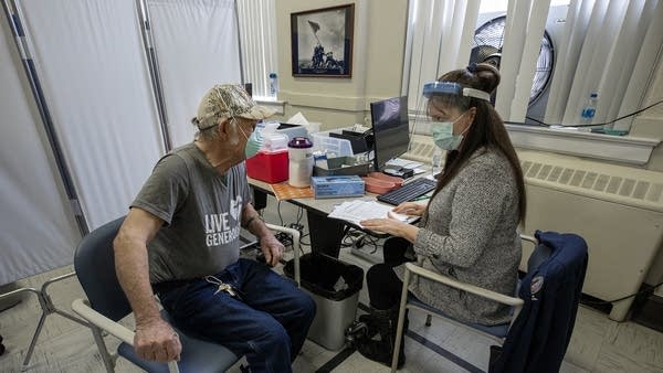 A nurse and a veteran sit at a desk.