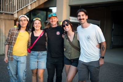 Five people pose for a photo ahead of a concert at an outdoor music venue