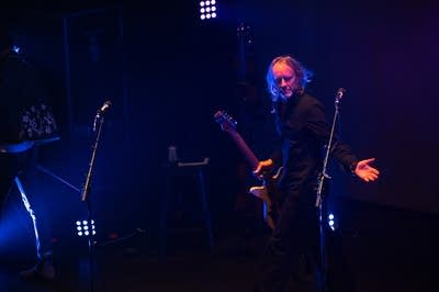 A musicians gestures warmly to an audience in theater