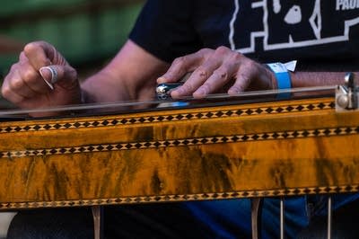 zoomed in photo of a man playing a pedal steel guitar
