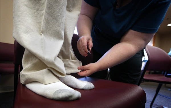 Michelle Ooley measures a pair of pants to make alterations.