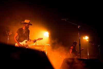 A musician plays guitar in a large music venue