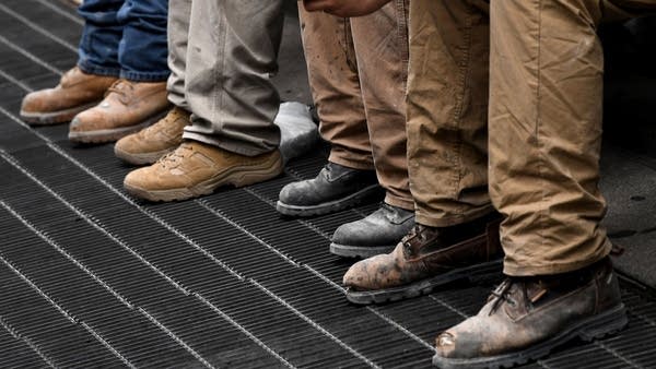 New York City construction workers line up over a street grate as they take their lunch break in midtown Manhattan on June 19, 2019 