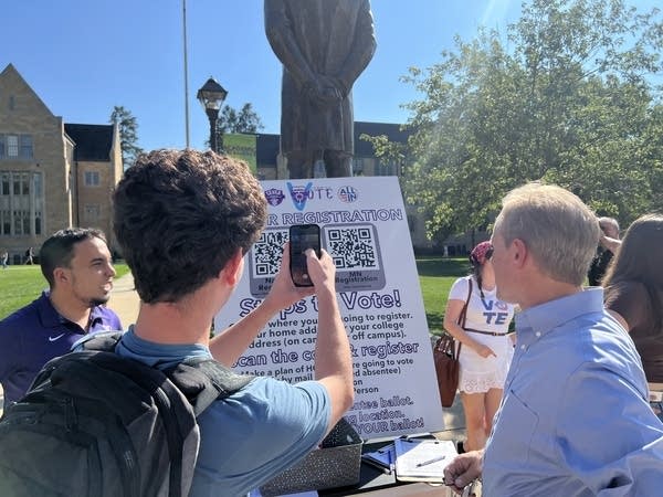 A young man uses his phone to take a picture of a poster