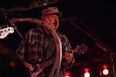 A musician sings and plays guitar on a large outdoor stage