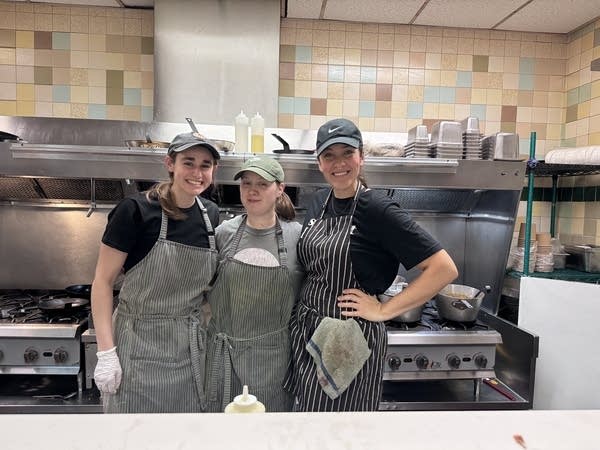 Three people pose for a photo in a kitchen