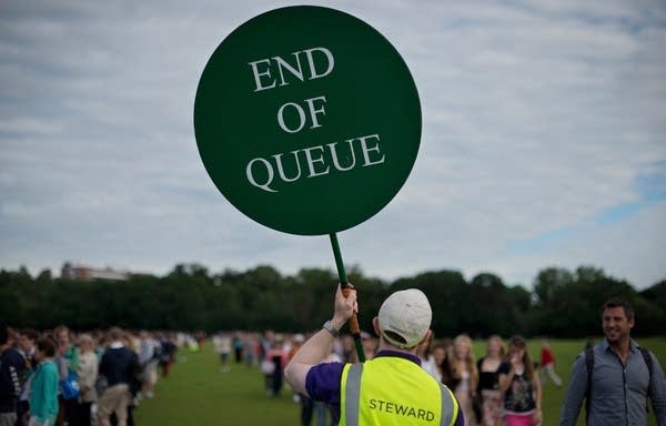 A steward holds a sign as tennis fans queue for tickets to watch the action at Wimbledon Championships tennis tournament at the All England Tennis Club in Wimbledon (Photo: BEN STANSALL/AFP/GettyImages)