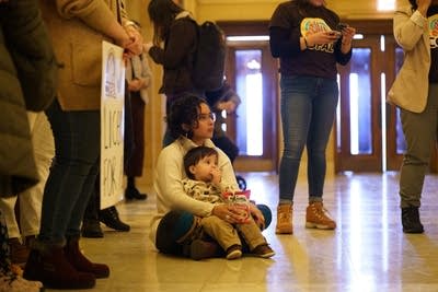 A woman sits with her baby on the floor